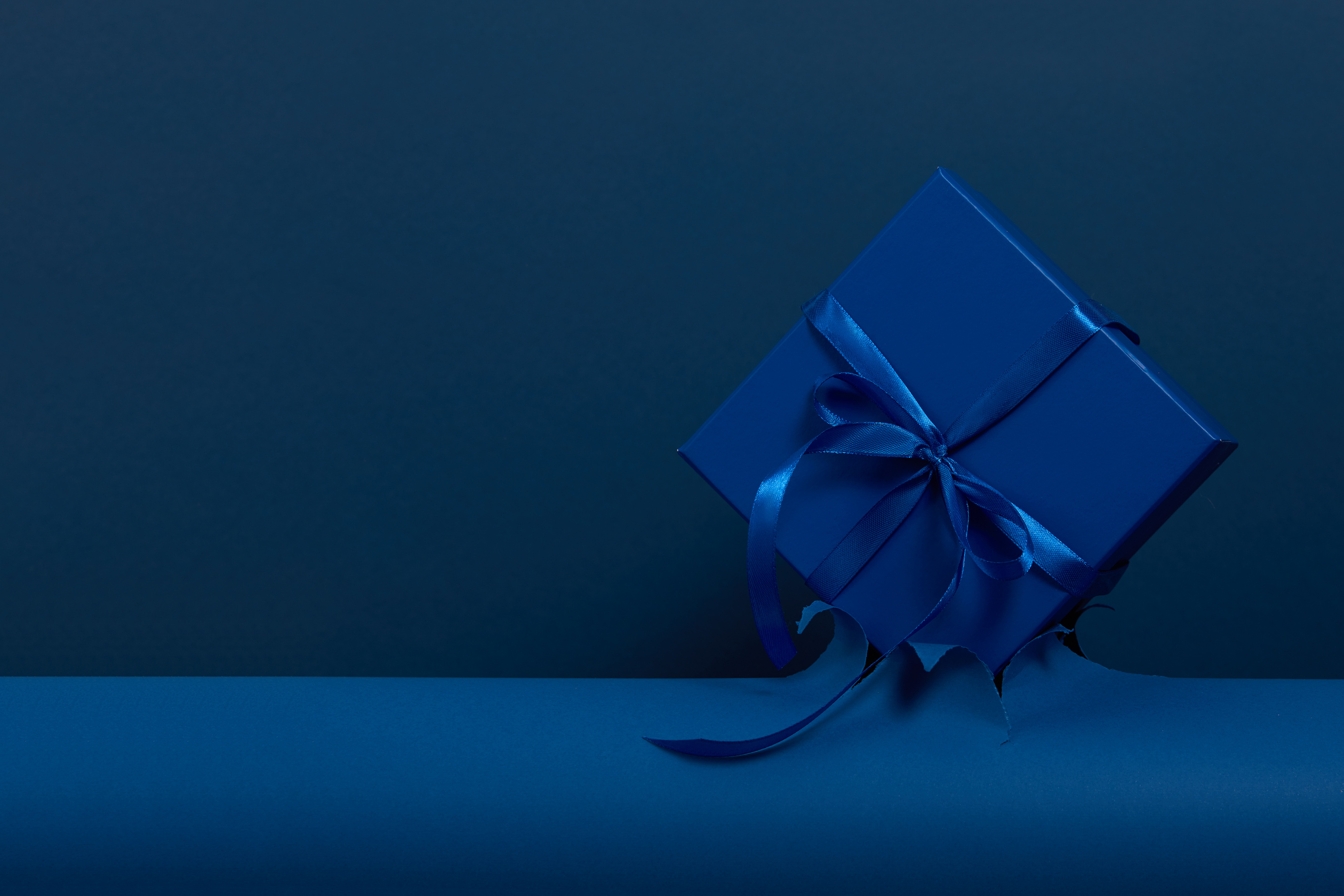 Blue gift box with bow on classic blue paper backround