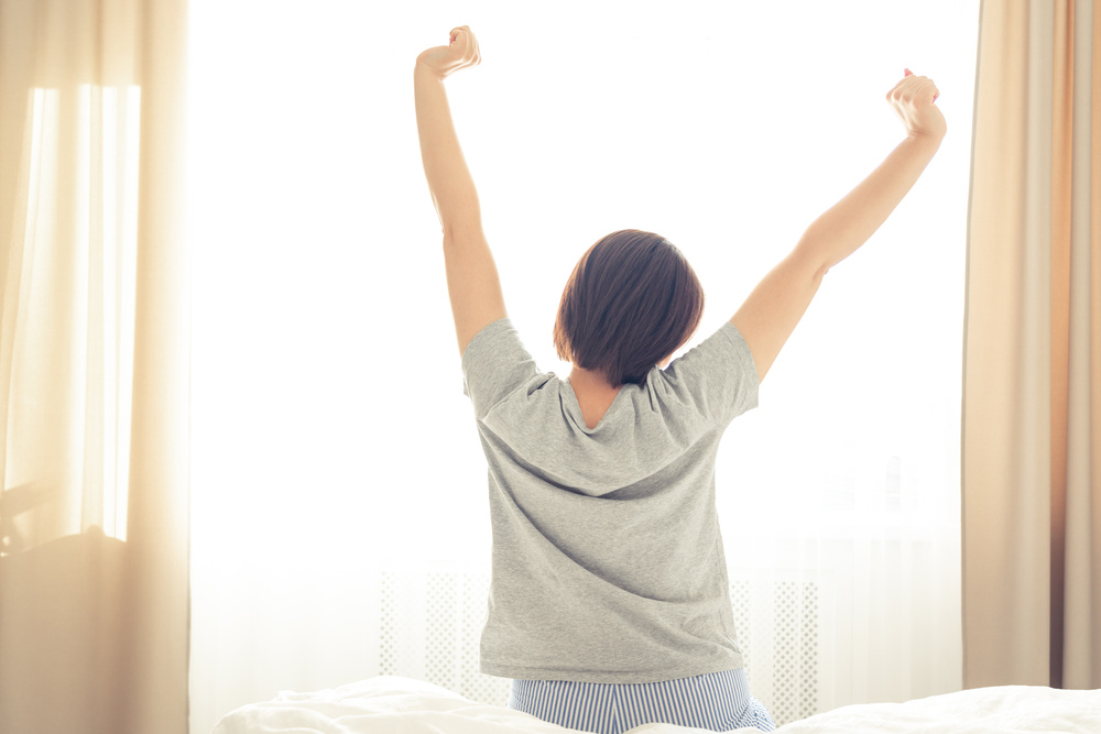 Woman stretching in bed room after good sleep