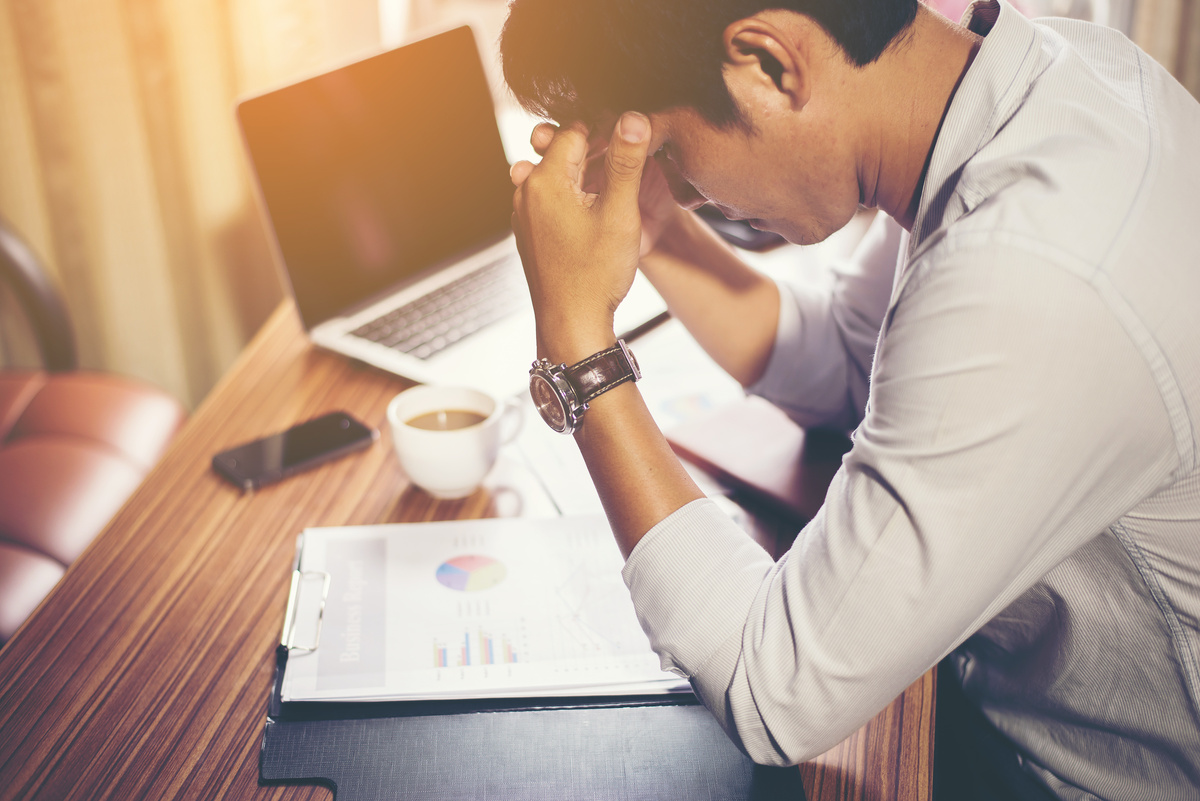 Man Holding His Head in front of Laptop